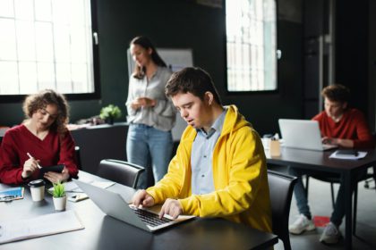 Down-syndrome man with laptop attending education class, inclusivity of disabled person.