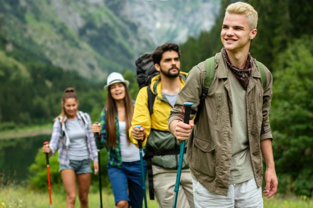Group of friends with backpacks doing trekking excursion on mountain