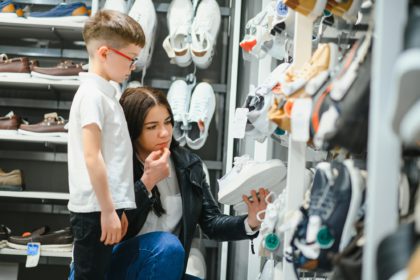 Mother with children choosing shoes in kids store