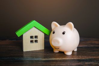Piggy bank near a house. Savings on household bills, energy saving technologies.