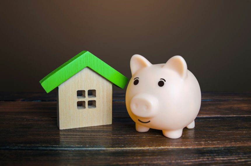 Piggy bank near a house. Savings on household bills, energy saving technologies.