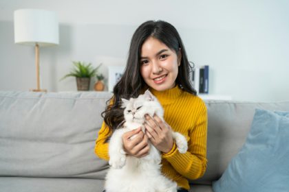 Portrait of beautiful woman holding little cat with happiness at home.