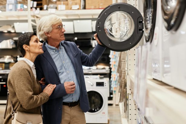 Senior couple looking at washing machines in appliance store