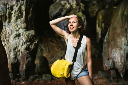 Young woman traveler at cave entrance on island hopping in Cheow Lan Lake