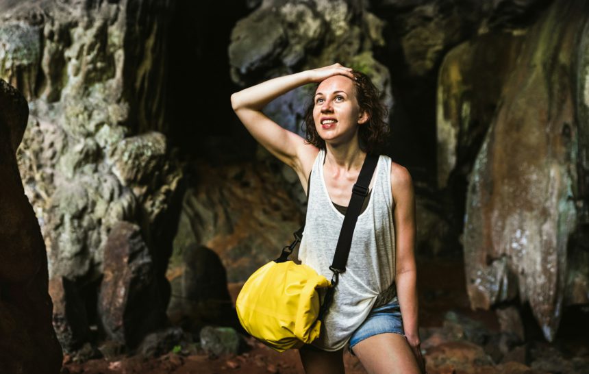 Young woman traveler at cave entrance on island hopping in Cheow Lan Lake